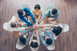 © deagreez - All together! Topview of businesspeople putting their hands on top of each other in nice light workstation, wearing casual clothes. Conception of successful teambuilding