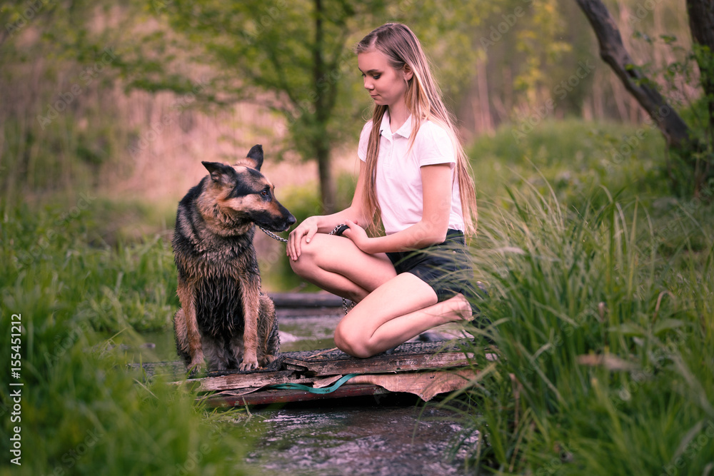 Teenage girl in white shirt with her dog sitting near the creek in the ...