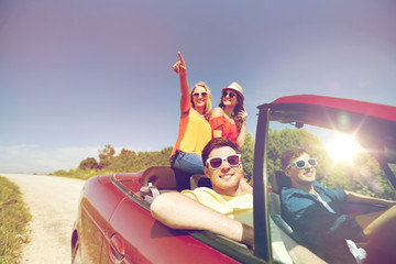 Wall Mural - happy friends driving in cabriolet car at country