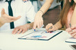 © cameravit - Group of business people looking at the clipboard with graphics.