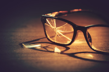 dramatic lit image of broken glasses on the floor / selective focus on the right eye