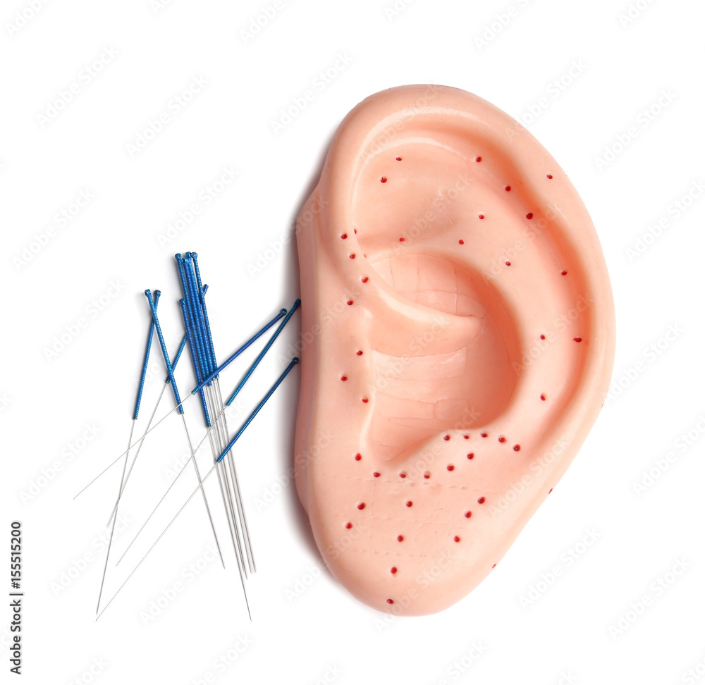 Needles for acupuncture and plastic mockup of human ear on white background