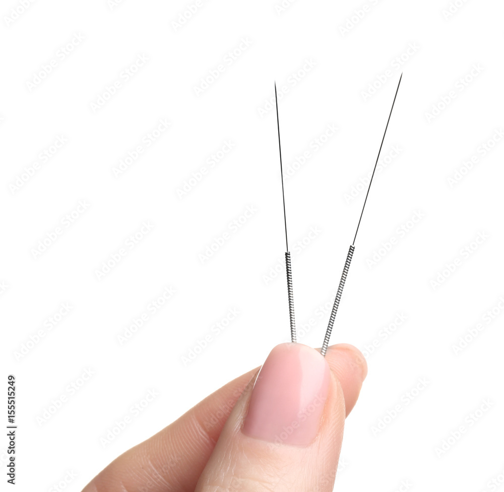 Female fingers with needles for acupuncture on white background
