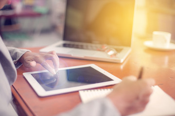 Beautiful business working woman using Ipad while working with laptop