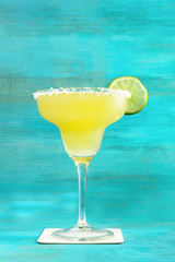 Wall Mural - Lemon Margarita cocktail on vibrant turquoise with copyspace