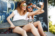 © BalanceFormCreative - Two female skaters friends sitting  on ramp  and hangout at the skate park .Taking selfie.