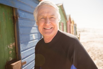 Portrait of senior man standing by beach huts