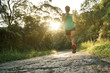 Female athlete running on sunrise forest trail