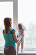 © satura_ - Loving mother playing with her baby son near a window