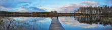 Panorama Landscape. Wooden Pier On The Lake At Sunset, Clouds Reflection In The Water.