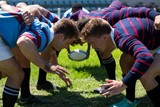 Close up of men playing rugby at grassy field