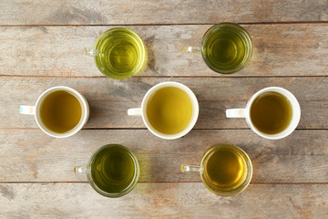 Poster - Cups of different tea on wooden table, top view