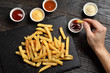 Hand dipping french fries in sauce
