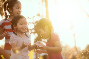 Wall Mural - blured image of asian children having fun to play with the rain together in the park in vintage color tone