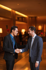 Canvas Print - Two Smiling Partners Shaking Hands in Lobby