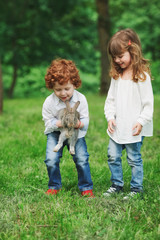 Canvas Print - little boy and girl playing with rabbit