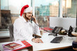 © Cookie Studio - Businessman smiling speaking on phone at worplace  christmas day.