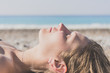 Attractive blonde woman with wet hair lies against the background of the sea shore