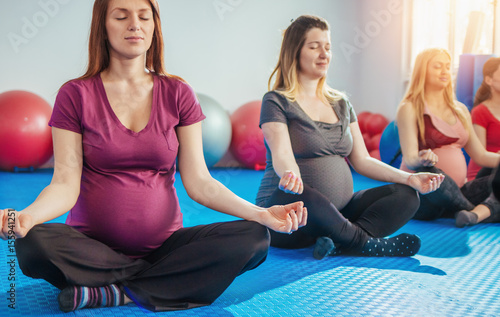 Plakat Grupa kobiet w ciąży medytacji na zajęcia jogi w pozycji lotosu