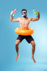 Young man jumping wearing swimming circle and glasses