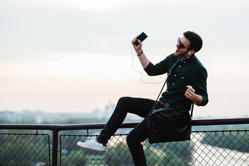 Wall Mural - Young man listening to the music on his smartphone