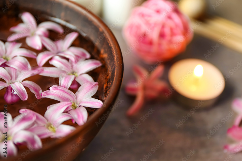Beautiful spa composition with flower petals on water and candle, closeup