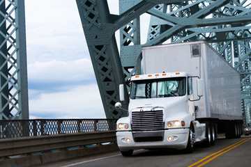 White Big rig semi truck and reefer on farm bridge