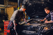 © Fxquadro - Two mechanics fixing car's engine in a garage.