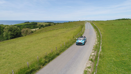 Wall Mural - Aerial view of bride and groom driving convertible car in countryside