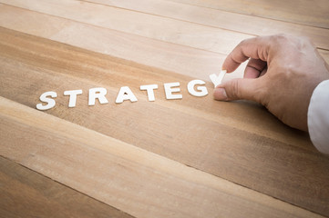 Wall Mural - Strategy word with male hand on wood table.Business marketing,analysis concept