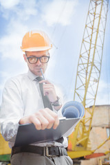 Engineer builder in a helmet holds drawings at construction site