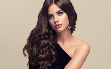 Brunette  girl with long  and   shiny wavy hair .  Beautiful  model with curly hairstyle .