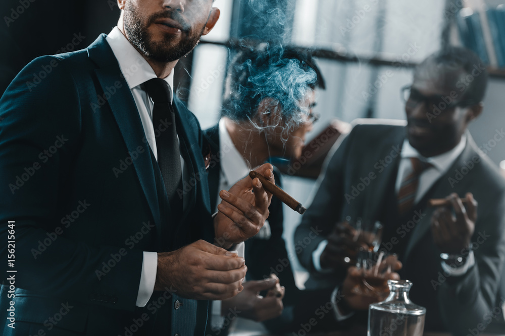 businessman smoking cigar with multicultural business team spending time behind - obrazy, fototapety, plakaty 
