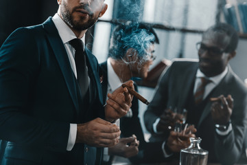 businessman smoking cigar with multicultural business team spending time behind