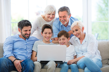 Wall Mural - Family using laptop on a sofa
