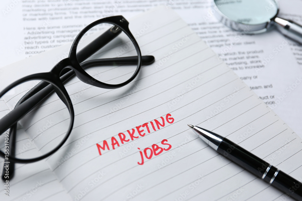 Open notebook with text MARKETING JOBS, closeup