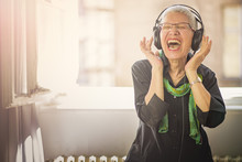 Senior Old Woman Listening To Her Favourite Music Through Big Headphones, Enjoying The Rich Sound