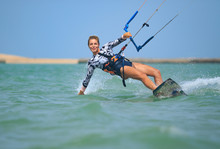 Kite Surfing Girl In Sexy Swimsuit With Kite In Sky On Board In Blue Sea Riding Waves With Water Splash. Recreational Activity, Water Sports, Action, Hobby And Fun In Summer Time. Kiteboarding Sport