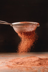 Natural cocoa powder in a sieve for chocolate and baking. Copy space.