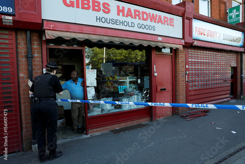 A Police Officer Speaks To A Man In A Hardware Store Next