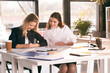 © LIGHTFIELD STUDIOS - Smiling young businesswomen working together at table with laptop