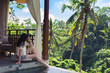 Girl sitting on the edge of the pool with a view of palm trees. Luxury holiday. Very nice view on the palm grove. Girl resting by the pool with a beauriful view of the palm trees on the island of Bali