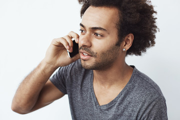 Wall Mural - Young handsome african man talking on phone over white background.