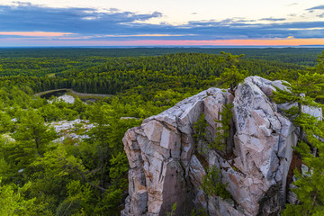scenic view of large rock formation from high cliff of lush forest horizon, killarney provincial par
