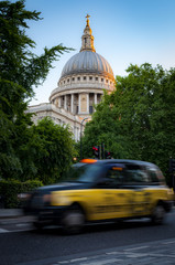 Wall Mural - Taxi cab passing by the english landmark that is St Paul's Cathedral surrounded by trees with green leafs in London, England, UK