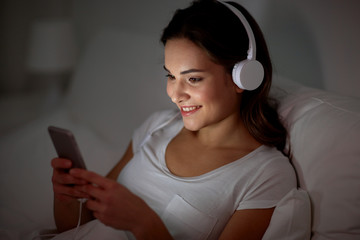 Poster - woman with smartphone and headphones in bed