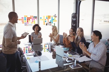 Business people applauding for colleague giving presentation