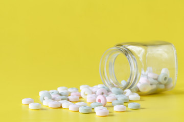 Colorful candies in jar on a yellow background