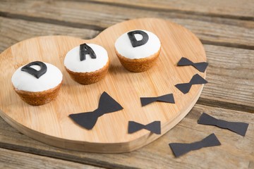 Wall Mural - Cupcakes with dad text by bow tie decoration on table