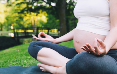 Wall Mural - Beautiful pregnant woman doing prenatal yoga on nature outdoors.